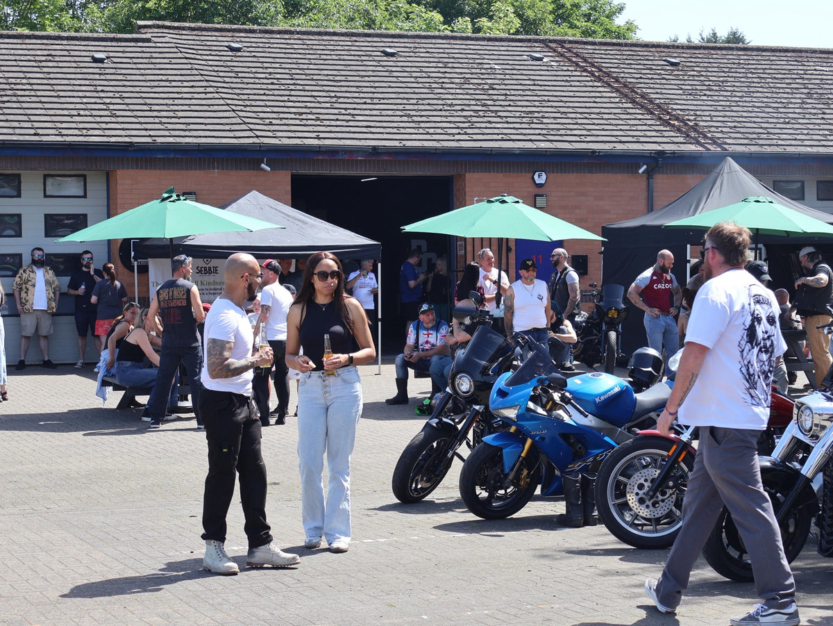 Guests chatting in front of the workshop and motorcycle line-up at the opening party.