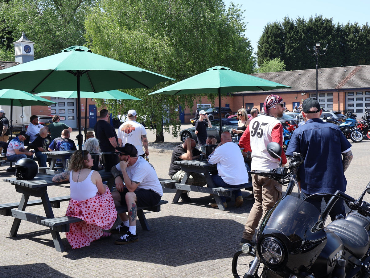 Riders chatting around picnic tables at a Deathproof community event.