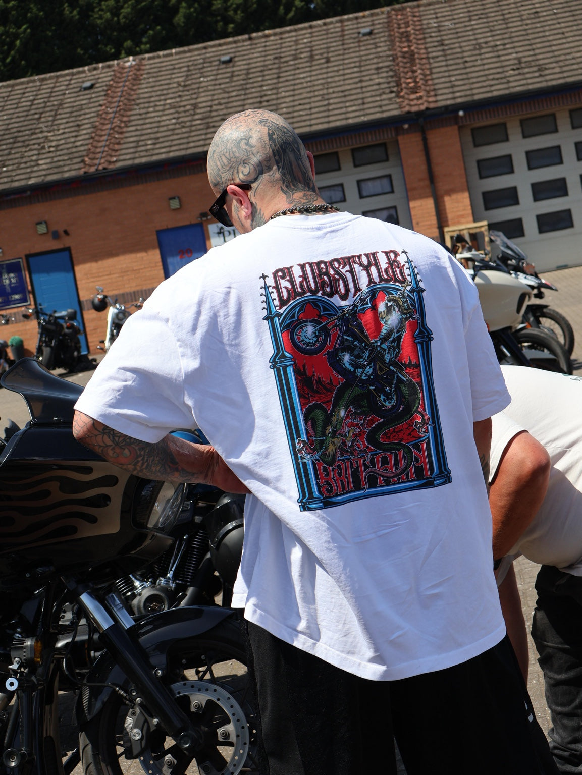 A guest wearing a Clubstyle Britain shirt beside motorcycles at the opening party.