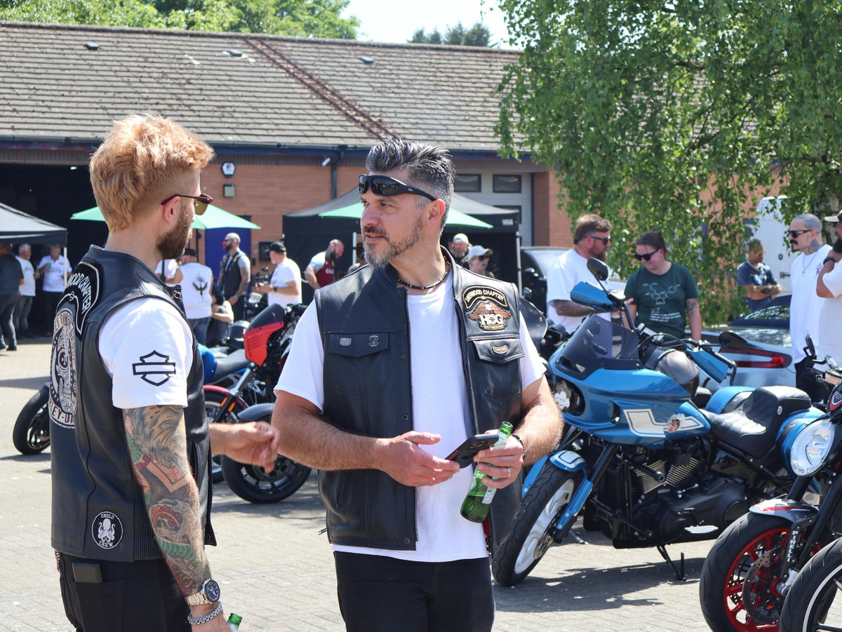 Two riders talking beside parked motorcycles at the opening party.