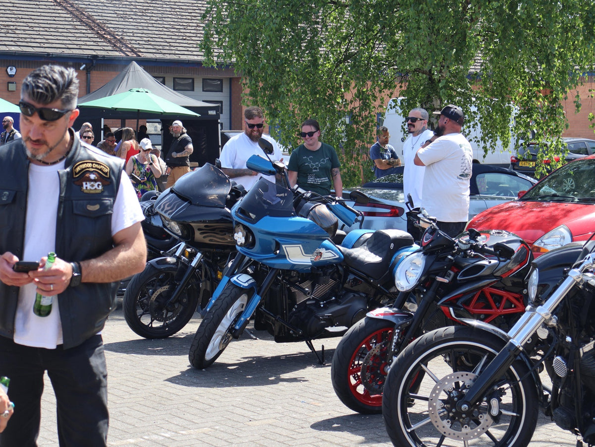 Guests chatting beside a row of motorcycles at the shop opening party.