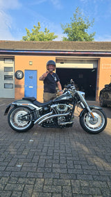 Ed smiling beside his motorcycle outside the workshop.